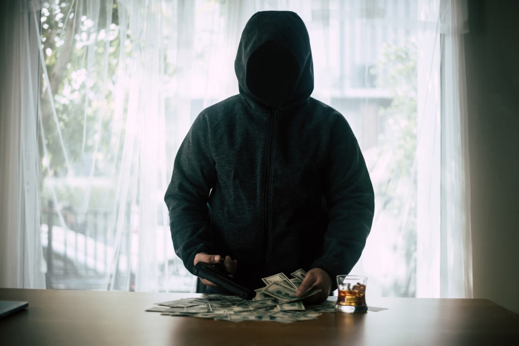 Hooded criminal gun shooting with dollar