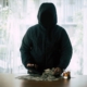 Hooded criminal gun shooting with dollar