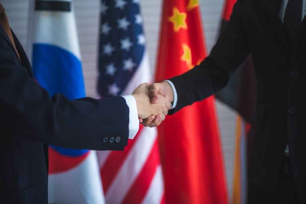 Business people shake hands, international flag background