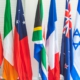 collection of various flags of different countries standing tall together in a row on a stand