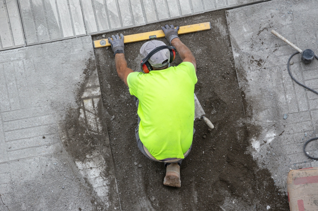 Construction worker with construction level working on a sidewalk