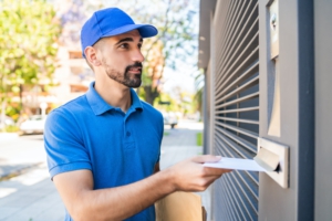 Postman putting letter in mailbox.