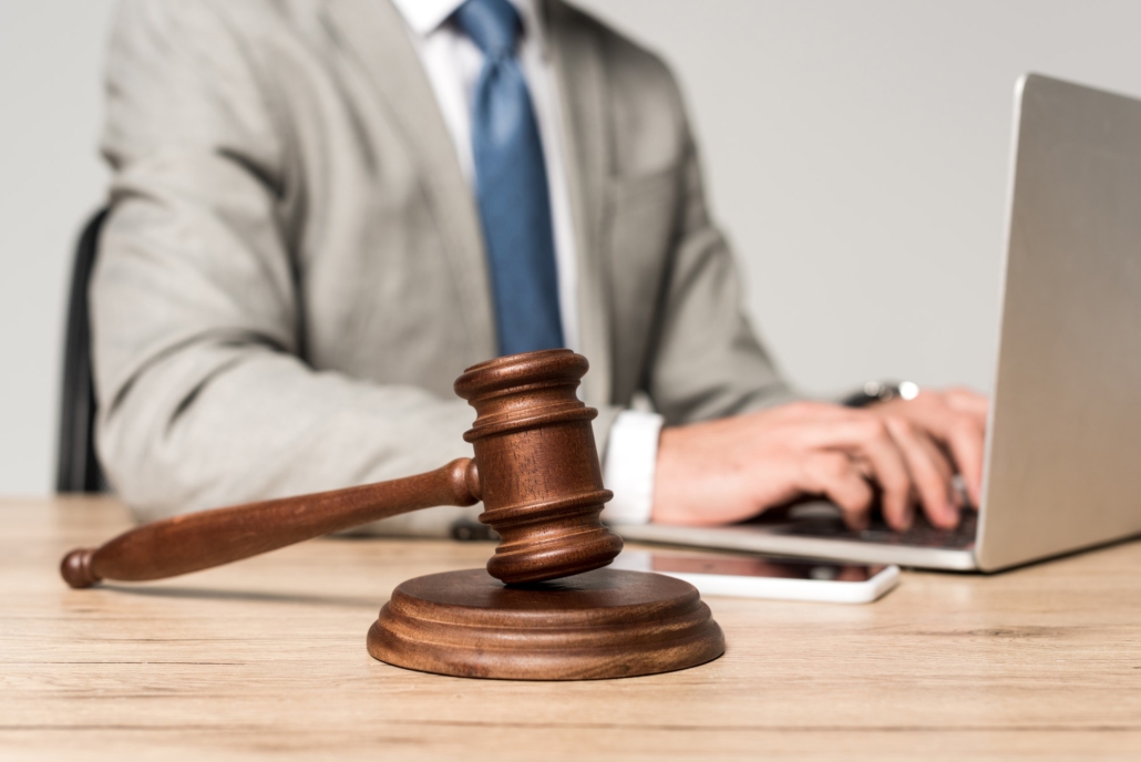 selective focus of gavel near lawyer working at laptop isolated on grey