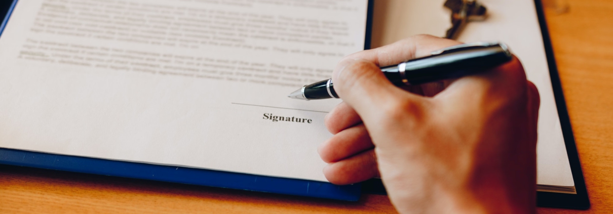 Hand client signing contract paper a real estate or mortgage contract.