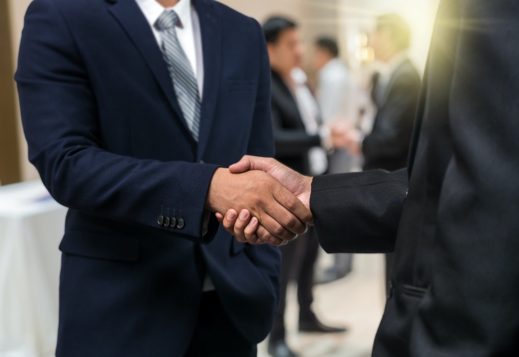 Business shaking hands of partner over the photo blurred of group of Businessman Corporate