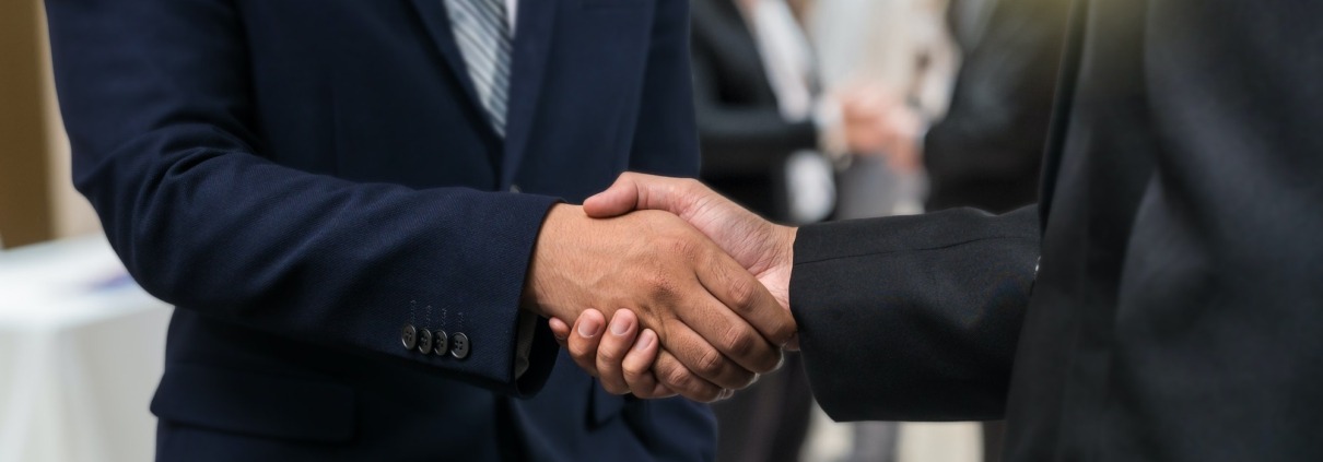 Business shaking hands of partner over the photo blurred of group of Businessman Corporate