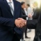 Business shaking hands of partner over the photo blurred of group of Businessman Corporate