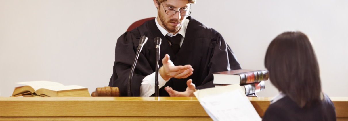 Present your case...Serious young judge sitting in the courtroom with a stern facial expression.