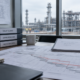 Projektbesprechung zu Verzögerungsschäden im Anlagenbau mit Terminplan vor einer Industrieanlage